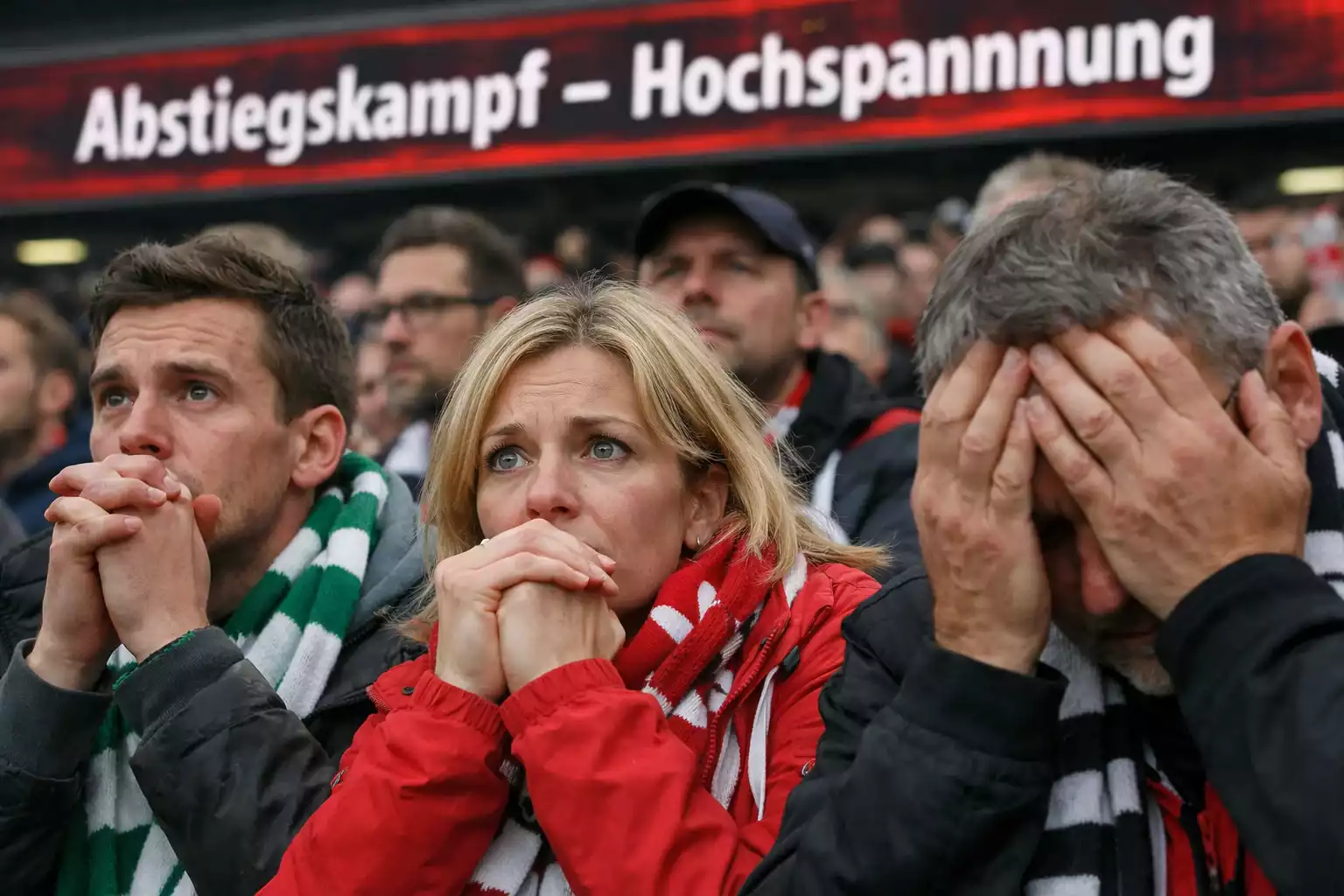 Angespannte Fußballfans im Stadion verfolgen ein entscheidendes Abstiegsspiel der Bundesliga